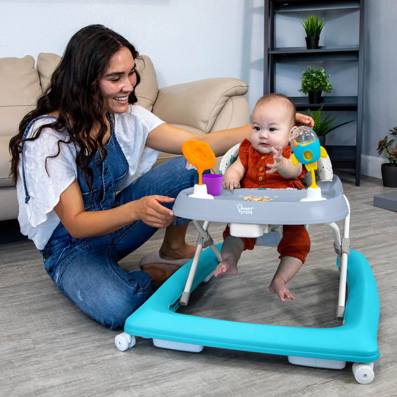 Mom is watching over her child while he plays in the Smart Steps by Baby Trend Trend Activity Walker
