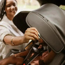 Load image into gallery viewer, A mother is adjusting the canopy on the Baby Trend Cover Me Convertible Car Seat to block the sun on her child face while driving