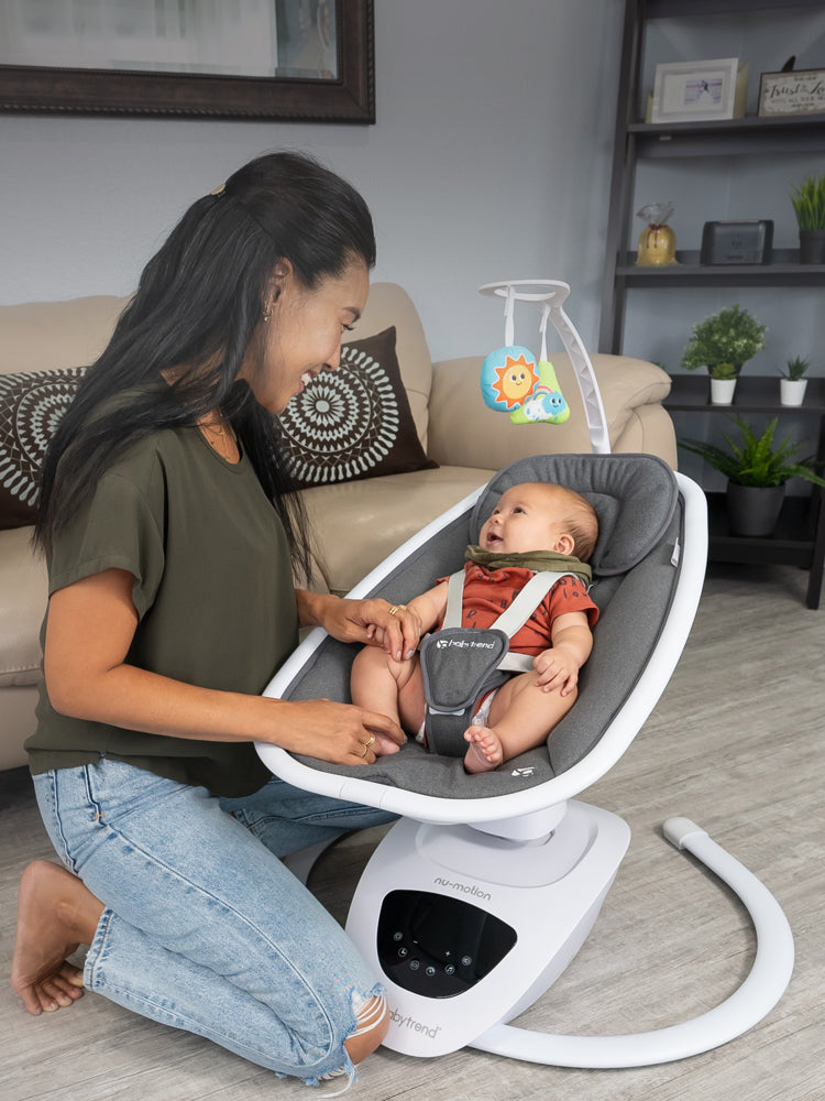 A mom is attending to her baby sitting in the Baby Trend NuMotion Infinity Swing