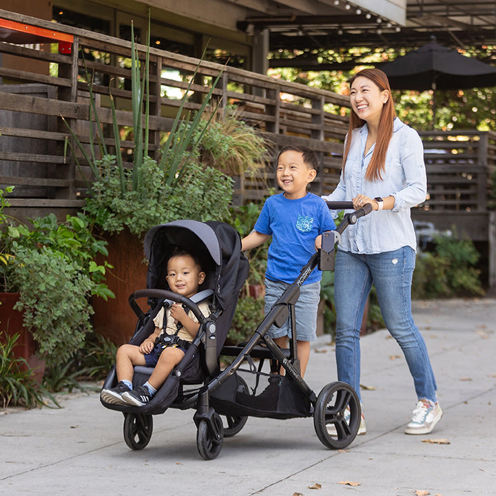 A mom is pushing her two children in the Baby Trend Morph modular stroller