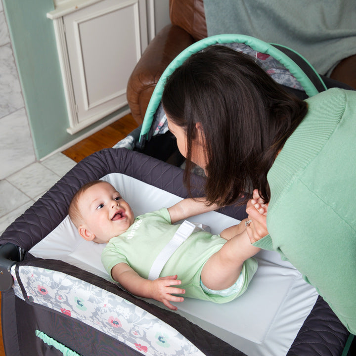 A mom is about to change her baby diaper using the changing table on a Baby Trend Nursery Center Playard