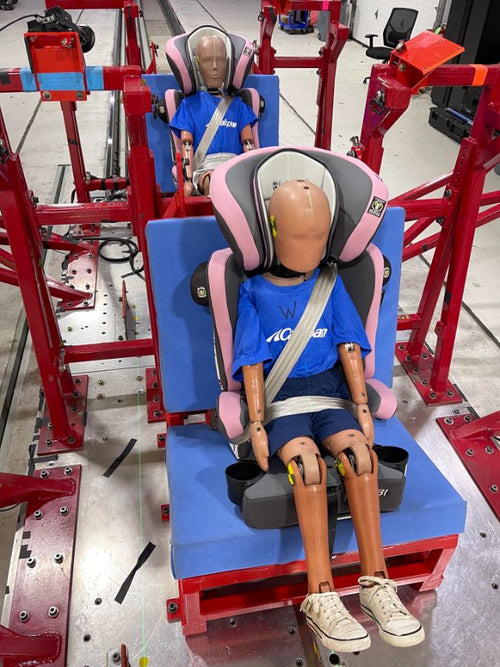 Two crash-test dummies belted into Baby Trend booster seats during a test run