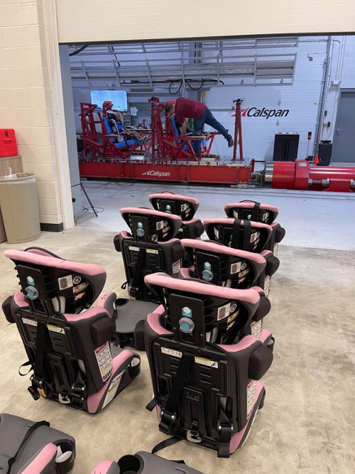 A row of pink Baby Trend car seats staged in the crash-test lab