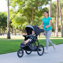 Load image into gallery viewer, Mom is out having a run with her toddler jogging with the Baby Trend Expedition Race Tec Plus Jogger Stroller