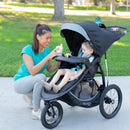 Load image into gallery viewer, Mother attending to her child sitting in the Baby Trend Expedition Race Tec Plus Jogger Stroller