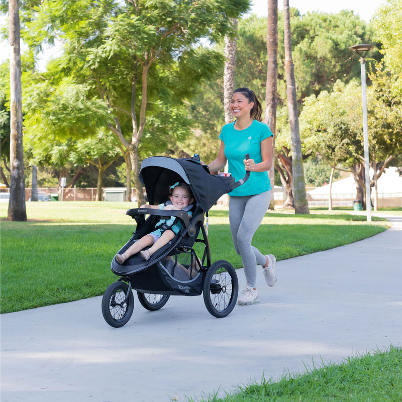 Mom jogging with her child in the park with the Baby Trend Expedition Race Tec Plus Jogger Stroller
