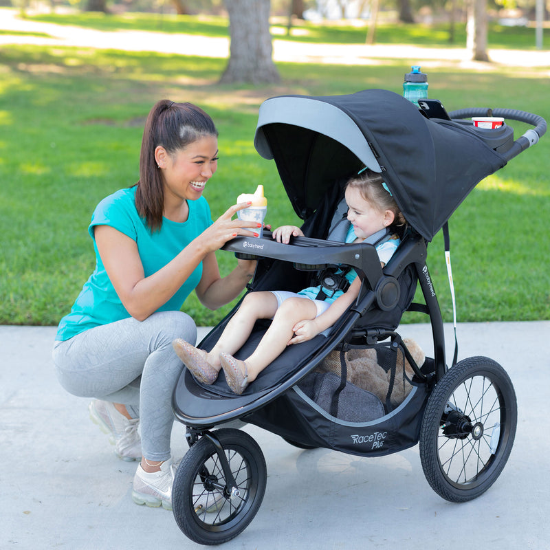 Mother attending to her child sitting in the Baby Trend Expedition Race Tec Plus Jogger Stroller