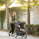 Load image into gallery viewer, Mother and child enjoying a stroll outdoor with the Baby Trend XCEL-R8 PLUS Jogger Stroller with LED light