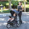 Mom is pushing her child in the Baby Trend Expedition Jogger Stroller outside 