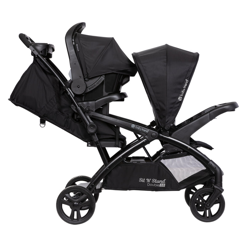 Side view of the Baby Trend Sit N' Stand Double 2.0 Stroller with infant car seat in the rear seat, infant car seat sold separately