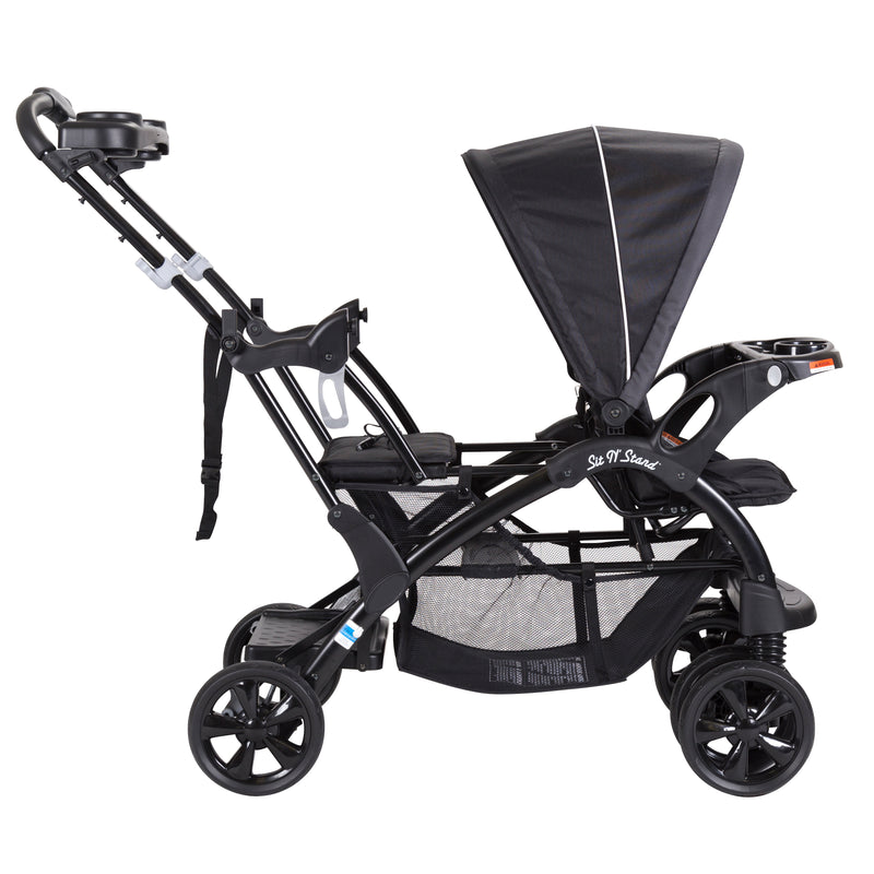 Baby Trend Sit N' Stand Double Stroller side view with child front seat and includes bench and stand on platform in the rear