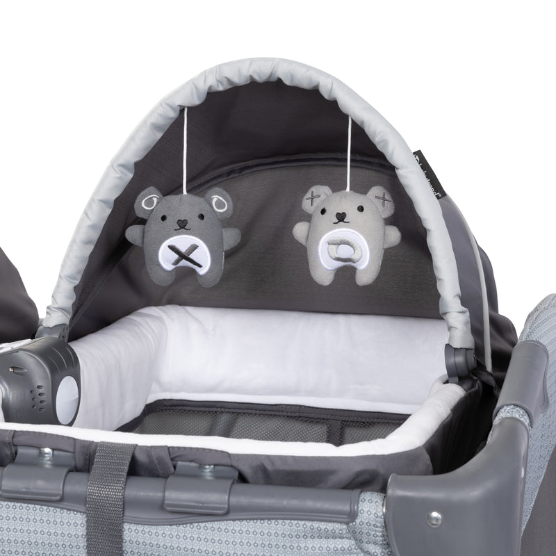 Baby Trend Lil’ Snooze Deluxe III Nursery Center Playard for Twins comes with two Rock-a-Bye Bassinet with two hanging toys