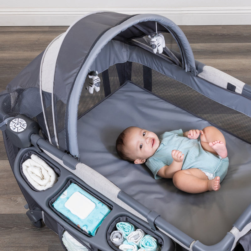 Baby is laying on the full-size bassinet of the Baby Trend Deluxe II Nursery Center Playard