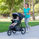 Load image into gallery viewer, Mother jogging with her child in the innovative Baby Trend Expedition Race Tec Plus Jogger Stroller