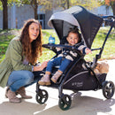 Load image into gallery viewer, Baby Trend Sit N Stand 5-in-1 Shopper Stroller of mom and child riding in the front seat
