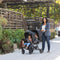 A mom is pushing her two children in the Sit N' Stand Double 2.0 Stroller