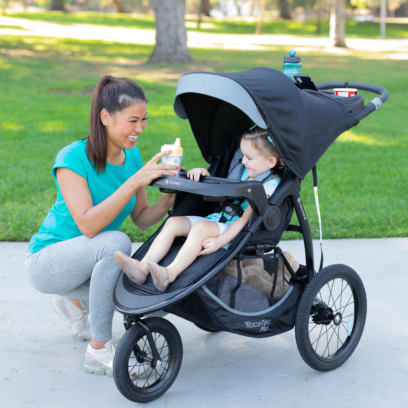 Mother is using the child tray with her child in the Baby Trend Expedition Race Tec Plus Jogger Stroller