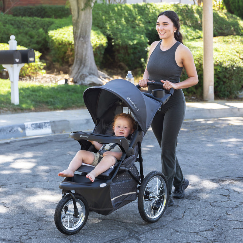 Mom is pushing the Baby Trend Expedition Jogger Travel System with her child sitting