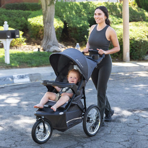 Mom is pushing the Baby Trend Expedition Jogger Travel System with her child sitting