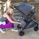 Load image into gallery viewer, Mom is accessing the storage basket from the rear of the Baby Trend Tango 3 All-Terrain Stroller Travel System