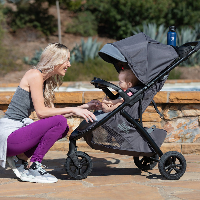 Mom is looking after her child outdoor in the Baby Trend Tango 3 All-Terrain Stroller Travel System with EZ-Lift 35 PLUS Infant Car Seat