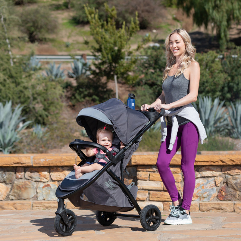 Mother is strolling with her child outdoor in the Baby Trend Tango 3 All-Terrain Stroller Travel System