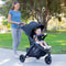 Mother is strolling her daughter in the park with the MUV by Baby Trend Tango Pro Stroller Travel System