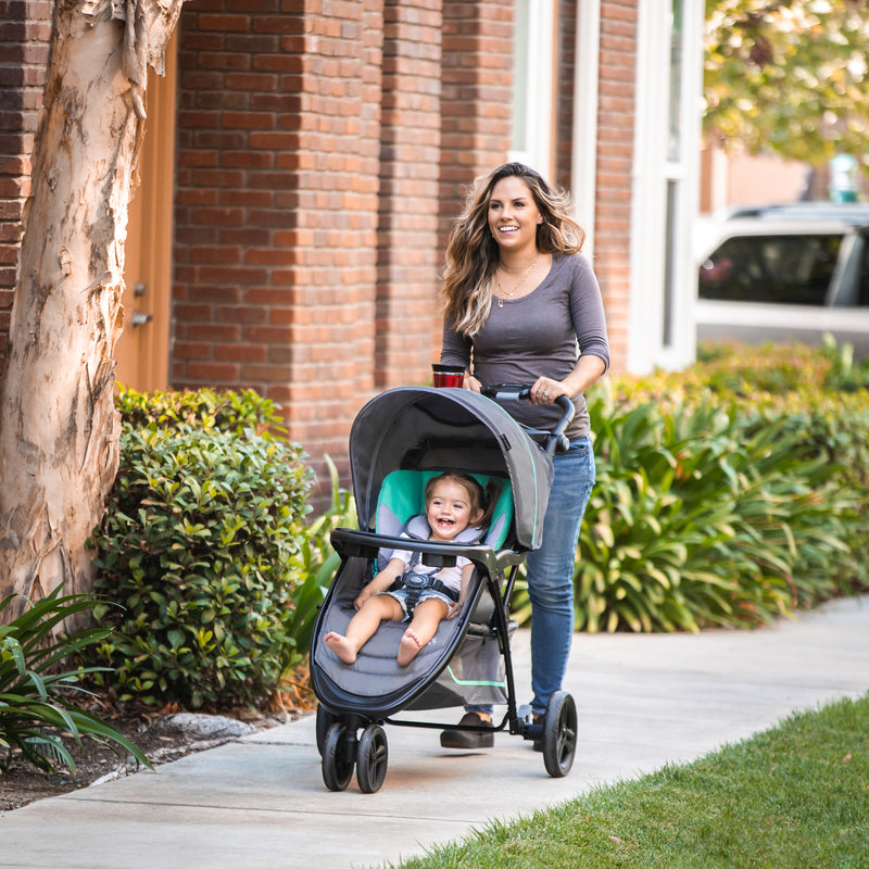 Mom is pushing her child outdoor with the Baby Trend EZ Ride Stroller Travel System with EZ-Lift 35 Infant Car Seat