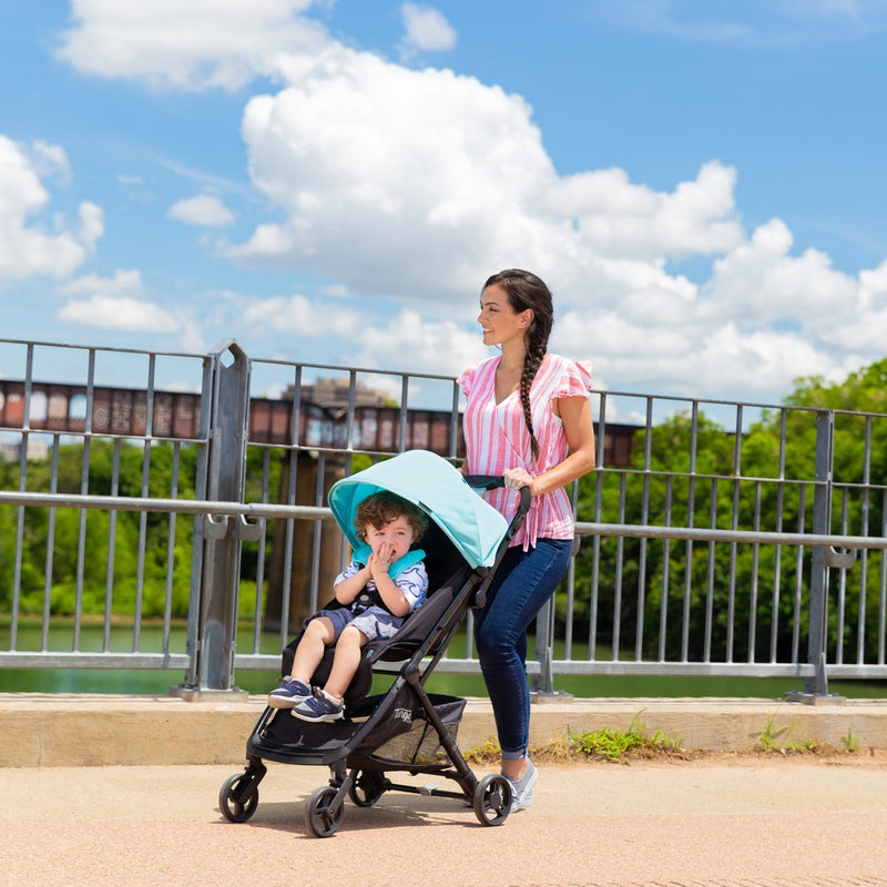 Mom and her child strolling through the outdoor exploring with the Baby Trend Tango Mini lightweight Stroller